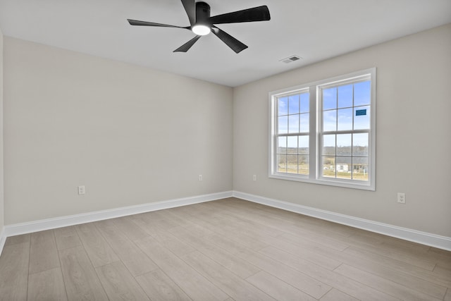 unfurnished room with wood finished floors, a ceiling fan, visible vents, and baseboards