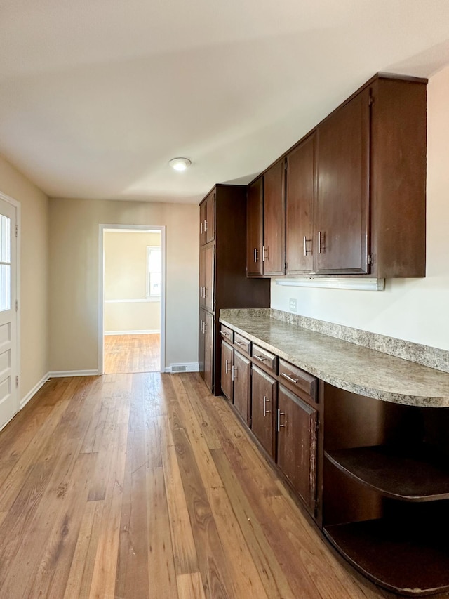 kitchen with dark brown cabinetry, plenty of natural light, and light wood-style flooring