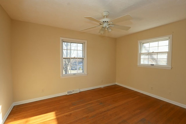 unfurnished room featuring visible vents, baseboards, wood finished floors, and a ceiling fan