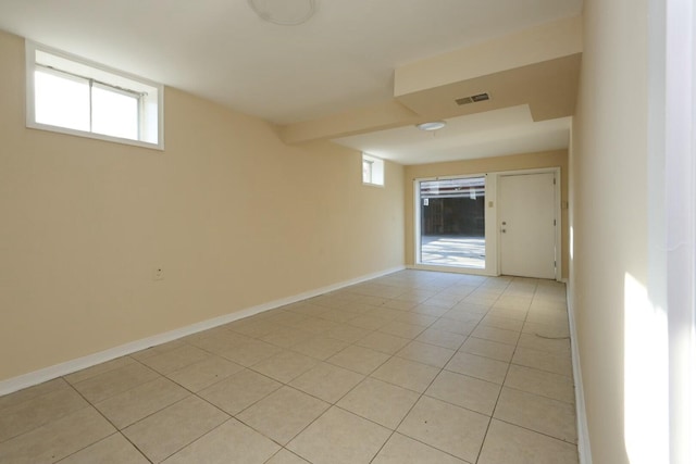 unfurnished room featuring a wealth of natural light, visible vents, baseboards, and light tile patterned floors