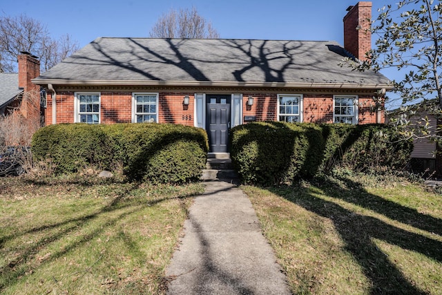 view of front of property featuring a front yard, brick siding, and a chimney