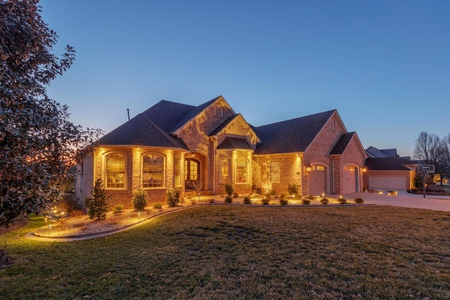 french provincial home with a lawn and brick siding