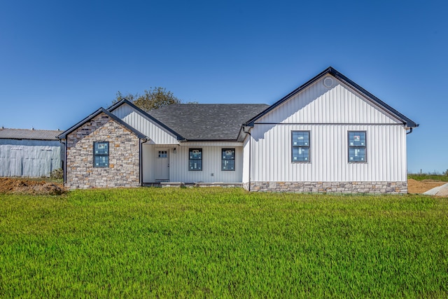 view of front facade with board and batten siding, a front lawn, and roof with shingles