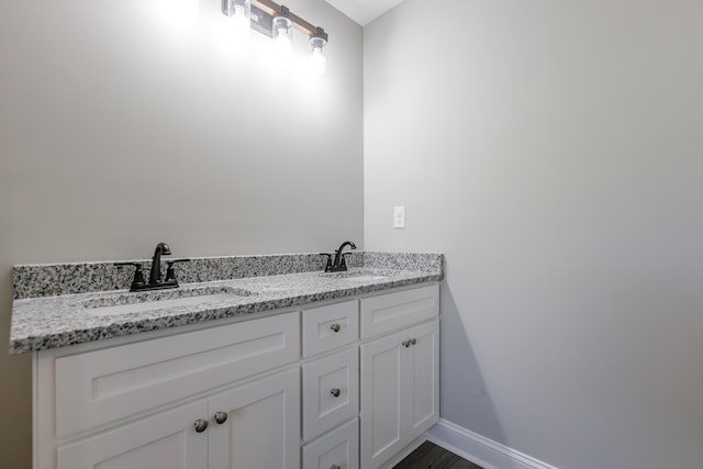 bathroom with a sink, baseboards, and double vanity