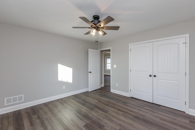 unfurnished bedroom featuring a ceiling fan, baseboards, visible vents, dark wood-style flooring, and a closet