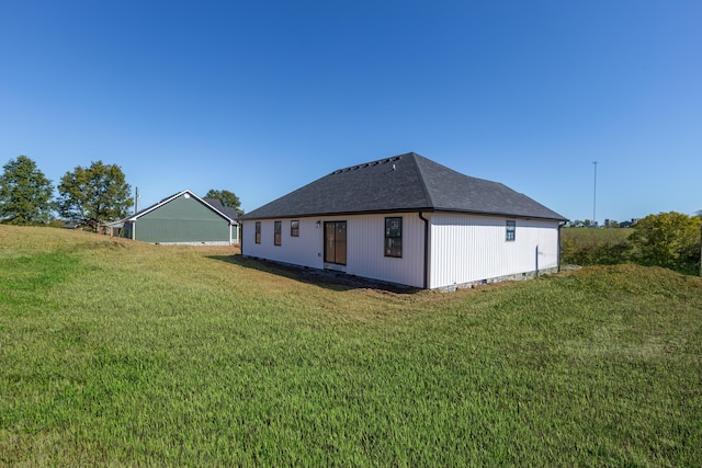 rear view of house with a lawn and roof with shingles