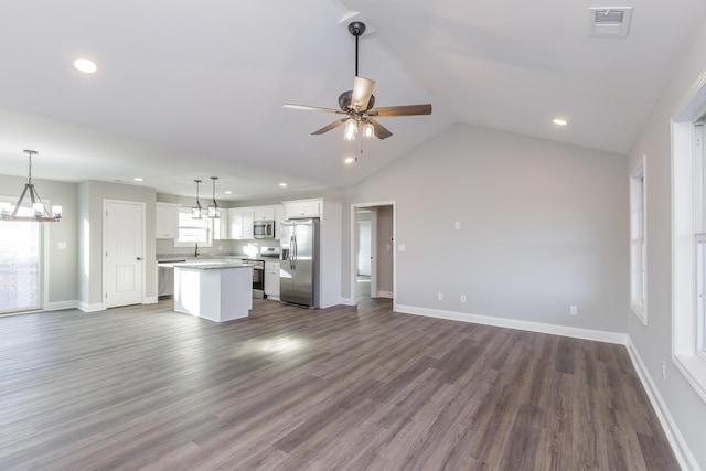 unfurnished living room featuring lofted ceiling, ceiling fan with notable chandelier, visible vents, and dark wood-style flooring