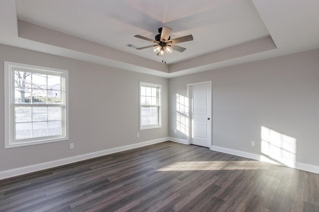 unfurnished room featuring baseboards, a raised ceiling, a ceiling fan, and dark wood-style flooring