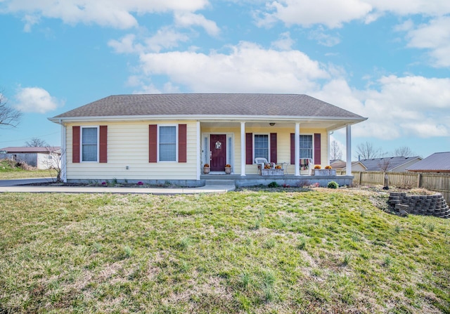 view of front of home with covered porch, a shingled roof, a front lawn, and fence