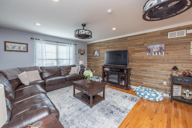 living room with recessed lighting, wood finished floors, visible vents, and wood walls