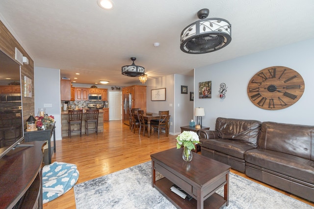 living room with recessed lighting, baseboards, and light wood finished floors