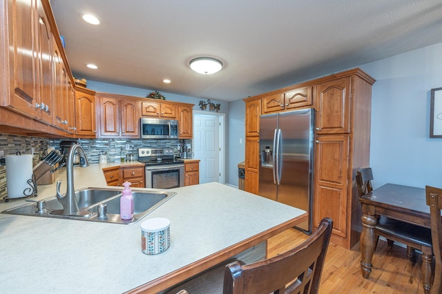 kitchen with a sink, backsplash, stainless steel appliances, a peninsula, and light countertops