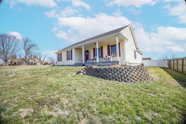 view of front facade with covered porch, a front yard, and fence