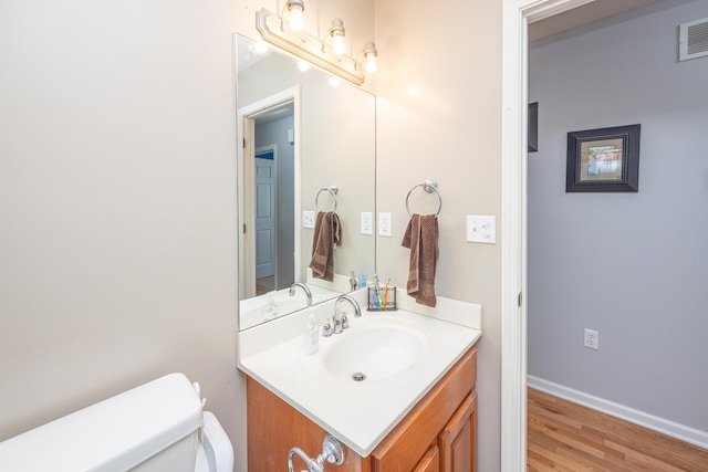 bathroom featuring vanity, wood finished floors, visible vents, baseboards, and toilet