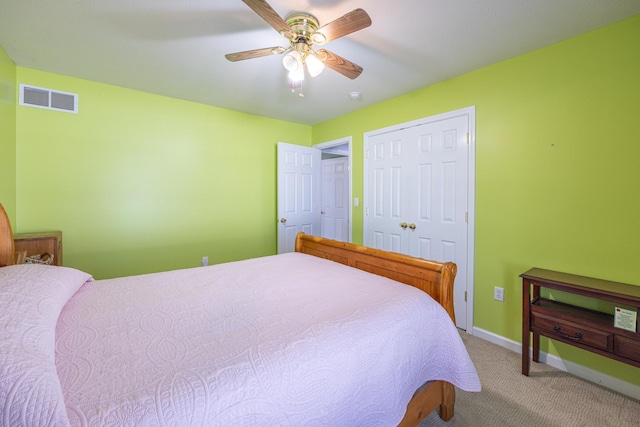 carpeted bedroom featuring a ceiling fan, visible vents, a closet, and baseboards