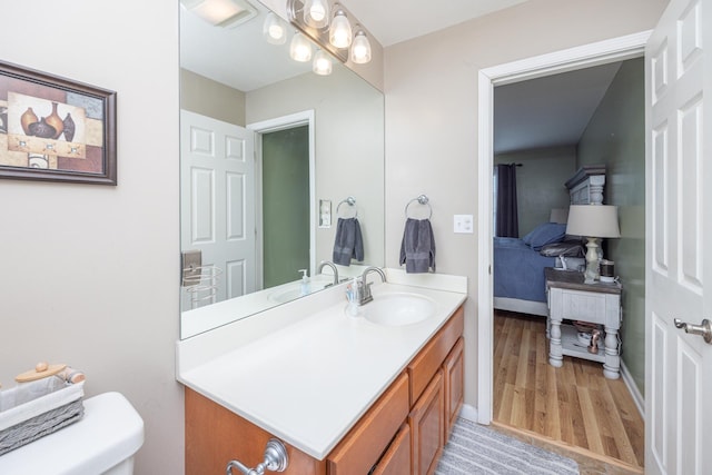 bathroom with baseboards, toilet, wood finished floors, and vanity