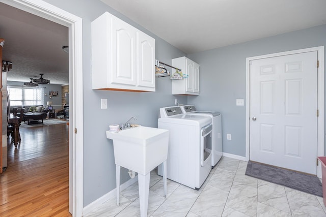 washroom with marble finish floor, washer and dryer, a textured ceiling, cabinet space, and baseboards