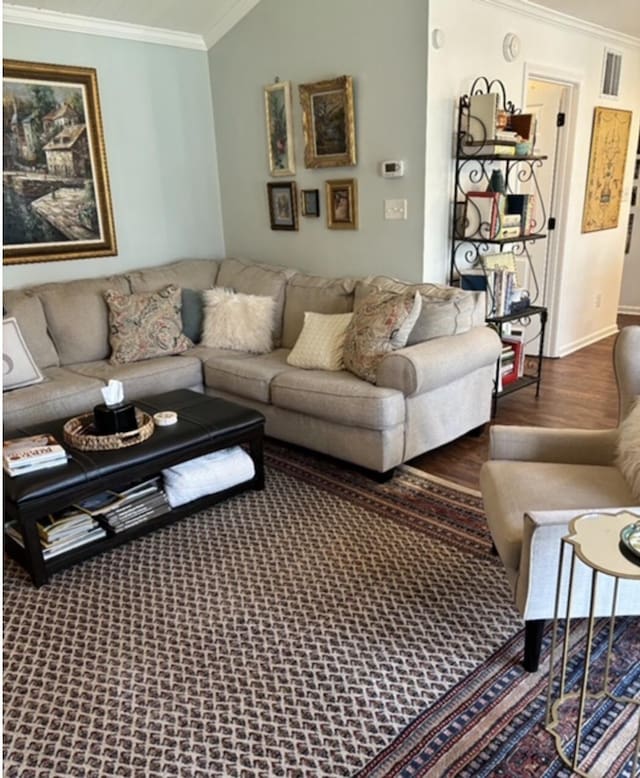 living area featuring baseboards, wood finished floors, visible vents, and ornamental molding