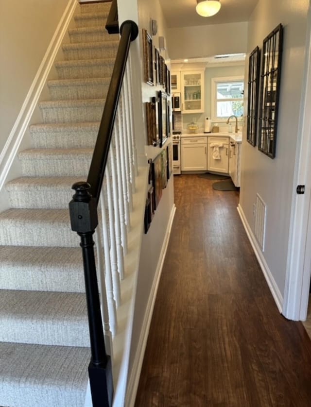 staircase featuring wood finished floors, visible vents, and baseboards