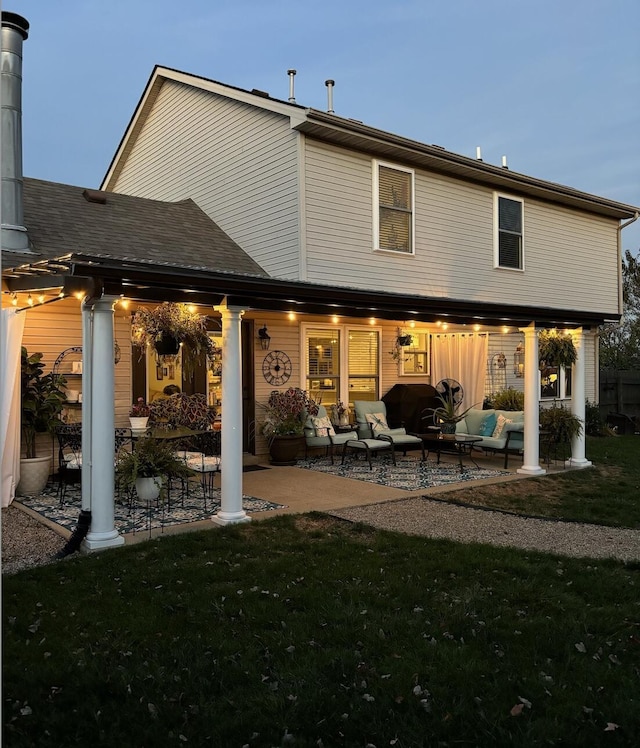 back of house with outdoor lounge area, a yard, a patio area, and roof with shingles