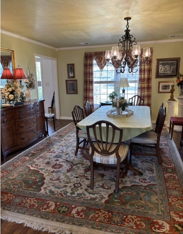 dining room featuring a textured ceiling, crown molding, an inviting chandelier, and wood finished floors