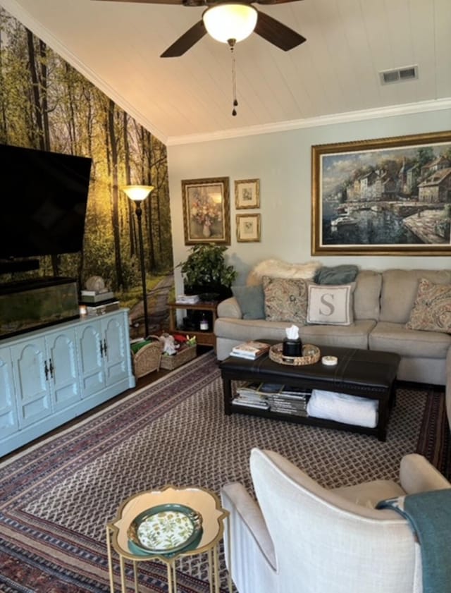 living area featuring visible vents, ornamental molding, and a ceiling fan