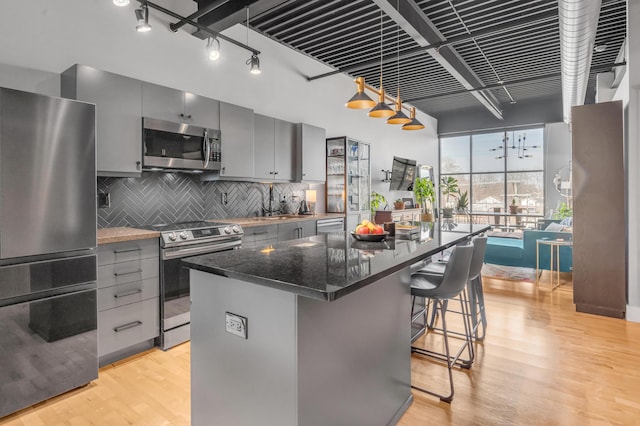 kitchen featuring a center island, gray cabinetry, stainless steel appliances, and light wood-type flooring