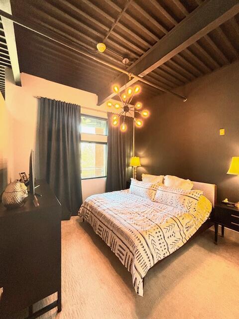 carpeted bedroom with beam ceiling and a chandelier