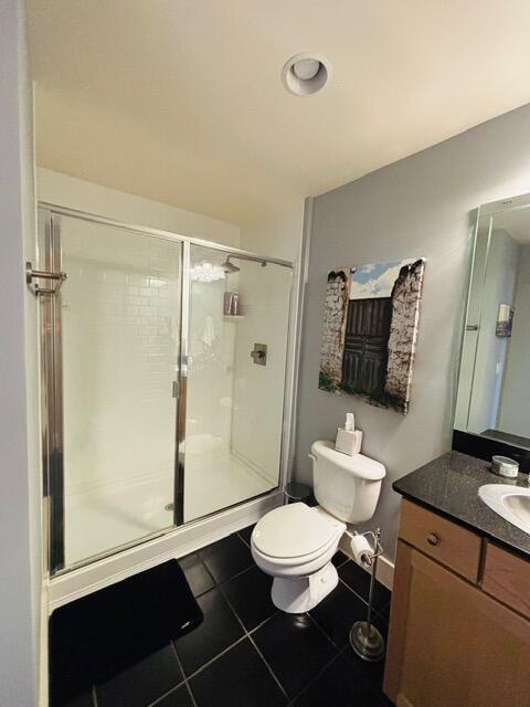 bathroom with vanity, tile patterned floors, toilet, and a stall shower