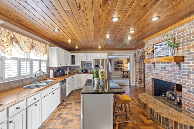 kitchen with backsplash, stainless steel appliances, brick floor, and a sink