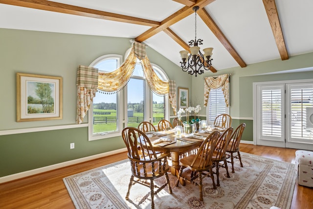 dining space featuring lofted ceiling with beams, a notable chandelier, wood finished floors, and a wealth of natural light