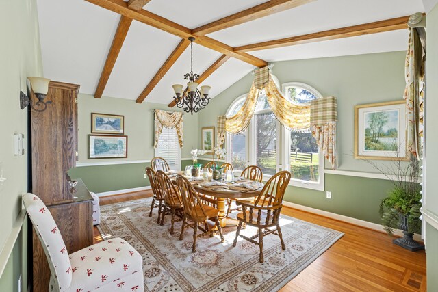 dining room featuring lofted ceiling with beams, baseboards, an inviting chandelier, and wood finished floors