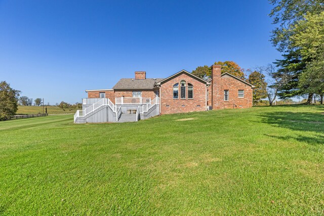 back of house featuring brick siding, stairway, a chimney, a yard, and crawl space