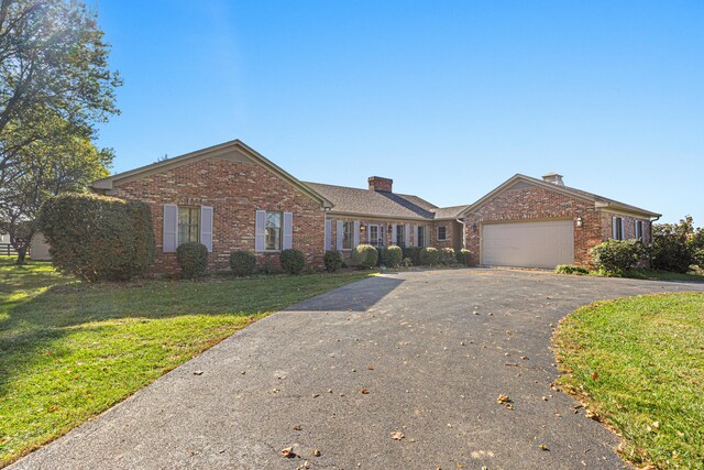 ranch-style home featuring brick siding, driveway, a front yard, and a garage