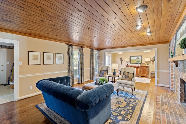 living room featuring wood finished floors, baseboards, a fireplace, crown molding, and wooden ceiling