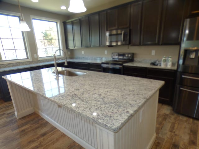 kitchen featuring a sink, dark wood-type flooring, light stone counters, and stainless steel appliances