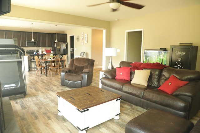 living area with light wood-type flooring, baseboards, and a ceiling fan