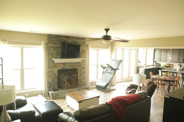 living area with wood finished floors, plenty of natural light, a fireplace, and ceiling fan