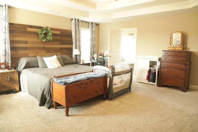 carpeted bedroom featuring a tray ceiling, wooden walls, and crown molding