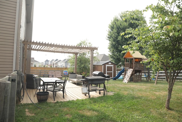 view of yard with a playground, fence, a wooden deck, a storage shed, and an outdoor structure