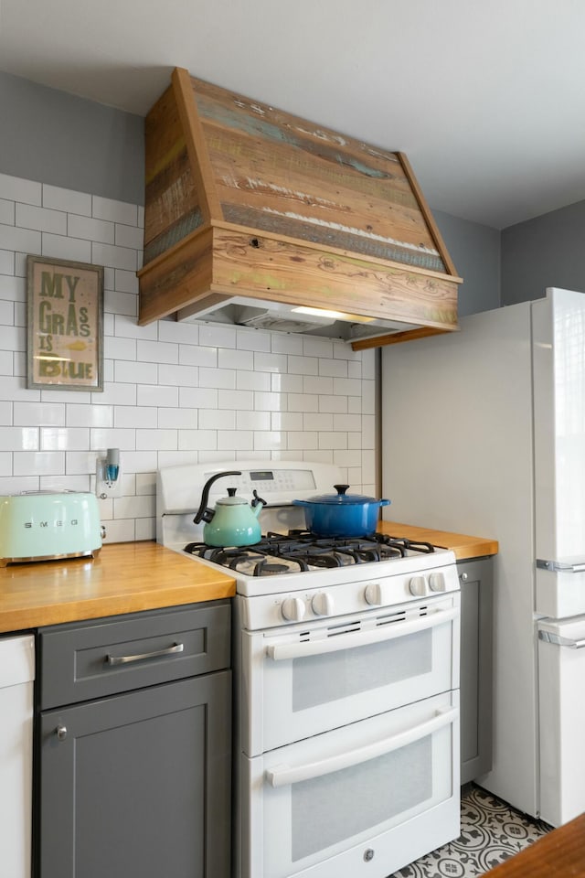 kitchen featuring backsplash, wooden counters, range with two ovens, gray cabinets, and custom exhaust hood