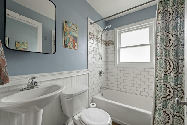 bathroom with toilet, shower / bath combo, a wainscoted wall, and a sink