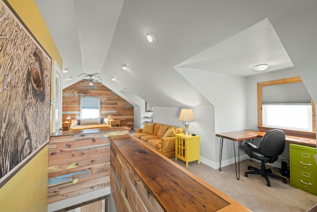 interior space featuring lofted ceiling, wooden walls, and baseboards