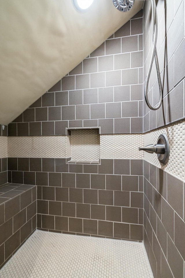 bathroom featuring a tile shower and vaulted ceiling