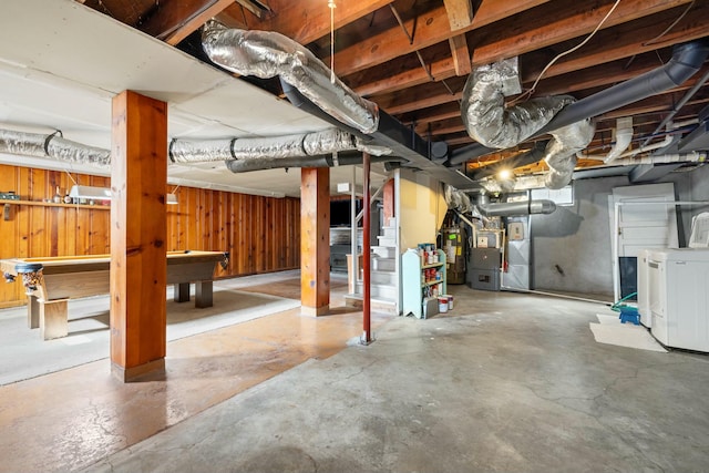 unfinished basement with wood walls, stairs, water heater, washer / dryer, and heating unit