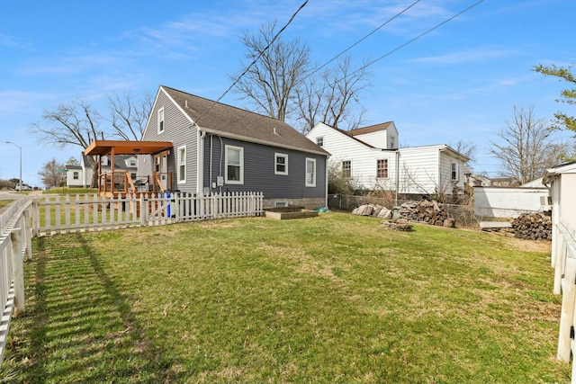 back of house with a fenced backyard, a lawn, and roof with shingles