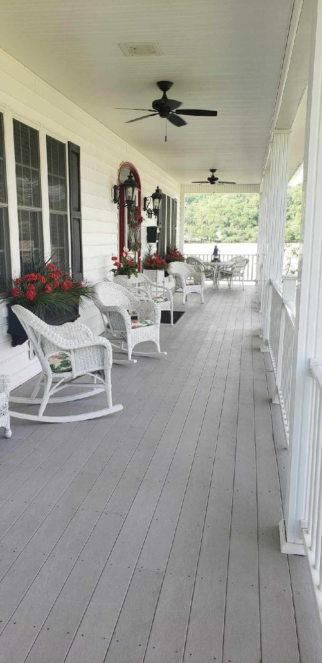 wooden terrace with visible vents, a porch, and ceiling fan