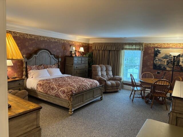 bedroom featuring carpet, crown molding, and wallpapered walls