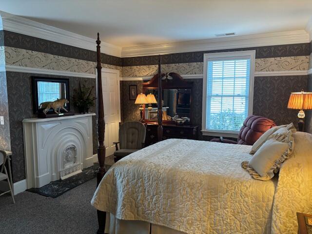 bedroom featuring visible vents, wallpapered walls, carpet, and ornamental molding