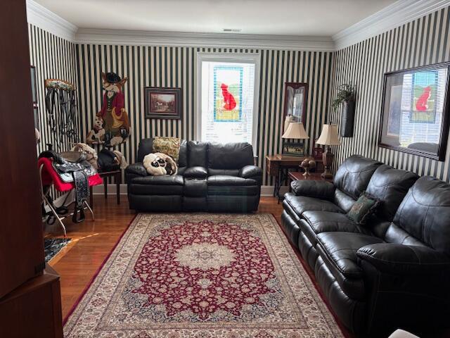 living area with wallpapered walls, crown molding, and wood finished floors